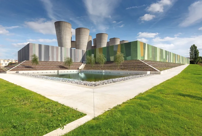 Effet d’optique du béton coloré. Les châteaux d’eau se prolongent dans le socle revêtu d’un parement en béton scintillant, se re étant dans une pièce d’eau biseautée.