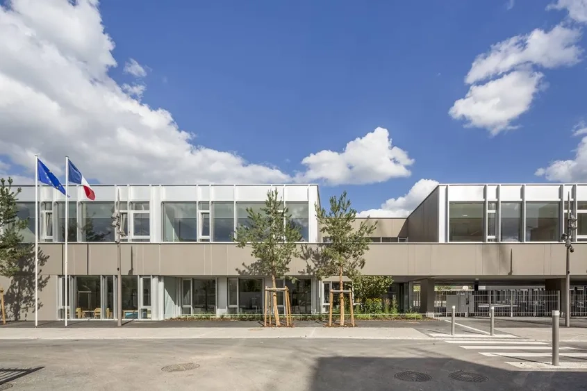 Vue sur l’école élémentaire, dont le préau se glisse sous le bâtiment pour signaler l’entrée et ouvrir la cour sur la promenade.