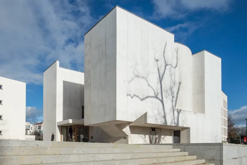 Façades sud et ouest. Très peu ouvert sur l’extérieur, l’édifice
se présente comme un ensemble de volumes imbriqués de béton blanc.
