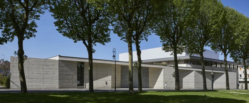 L’entrée face à la place, où le paravent de béton calcaire assoie l’aimable monumentalité d’un équipement culturel ouvert sur la ville.