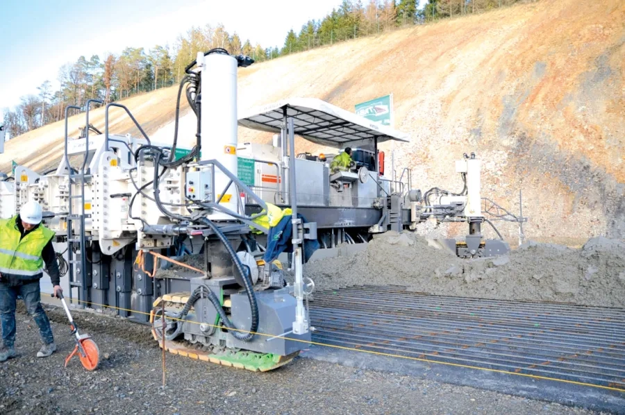 Assurant en une seule opération le coffrage et la vibration, la première machine à coffrages glissants (Wirtgen SP 1500) bétonne sur 17 cm d’épaisseur et sur 10 m de largeur. Au premier plan, le fil de guidage. Assurant en une seule opération le coffrage et la vibration, la première machine à coffrages glissants (Wirtgen SP 1500) bétonne sur 17 cm d’épaisseur et sur 10 m de largeur. Au premier plan, le fil de guidage.